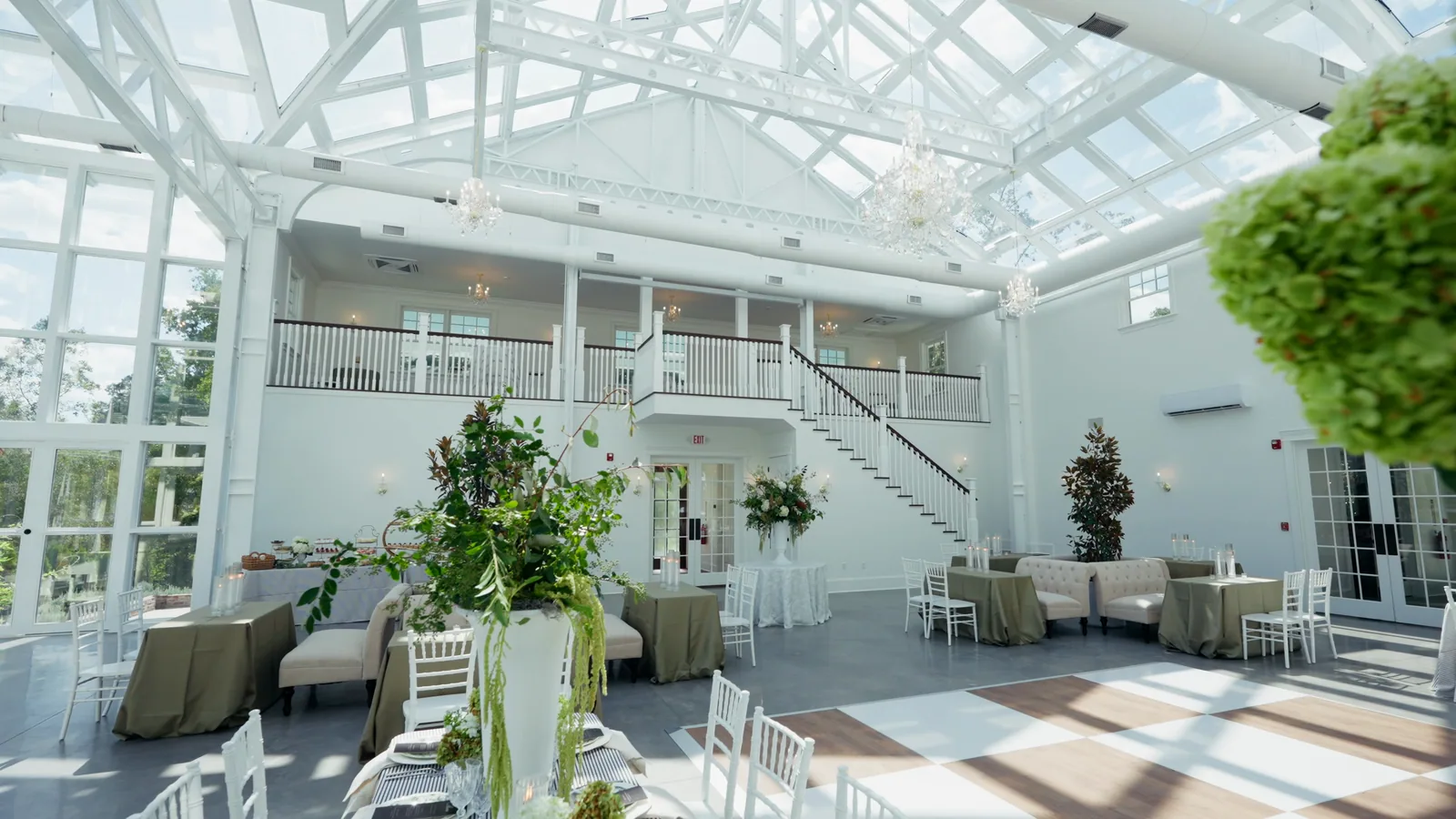 Inside the conservatory: a vaulted glass roof, the balcony above, tables set below